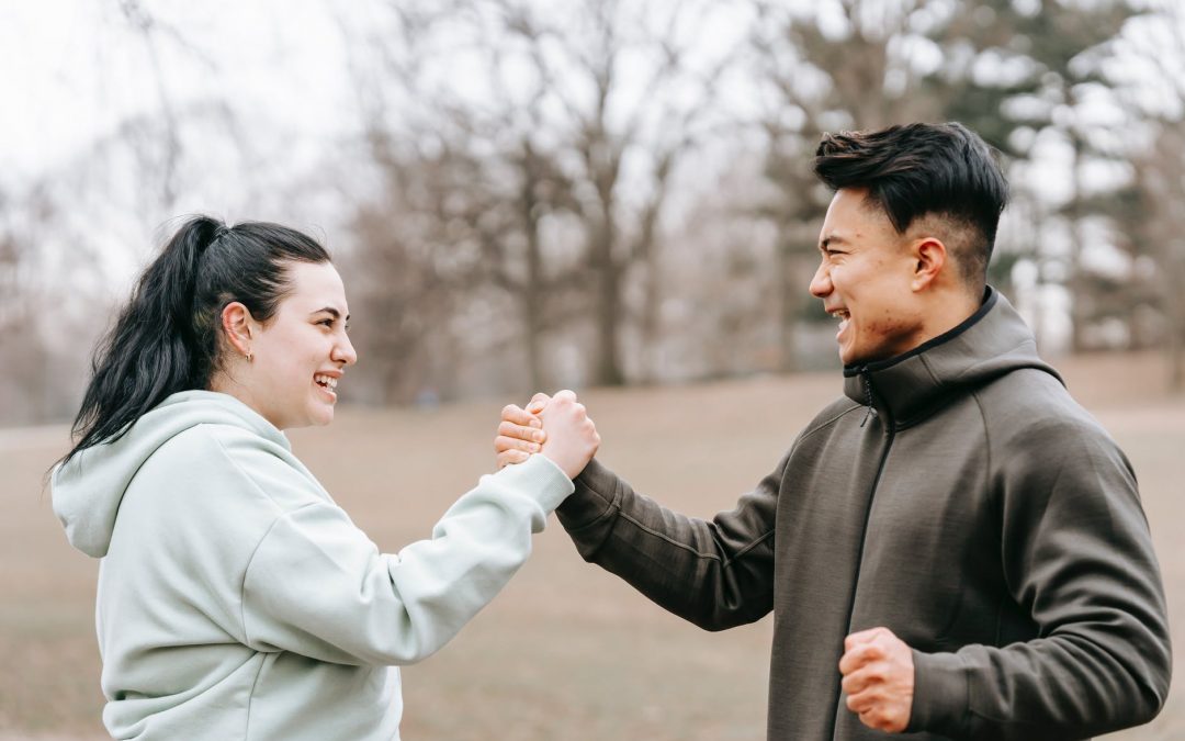 young positive asian trainer supporting and giving hand to woman
